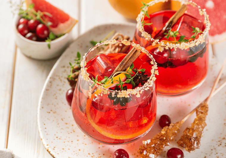 Cranberry spice mocktail with cinnamon stick, orange slice, and sugared rim | Angelia Mendoza