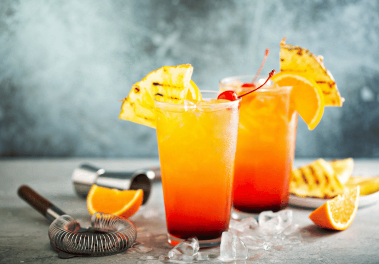 Pineapple sunrise mocktail with cherry, orange, and grilled pineapple garnish | Angelia Mendoza
