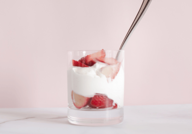 Glass of strawberry parfait layered with yogurt and fresh strawberries against a soft pink background, illustrating how nutritional mistakes can hide in seemingly healthy foods.