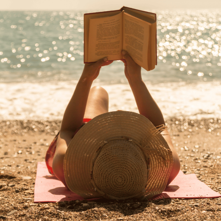 Empower Yourself: The Ultimate Book List For Women Over 40 | Woman reading a book on the beach