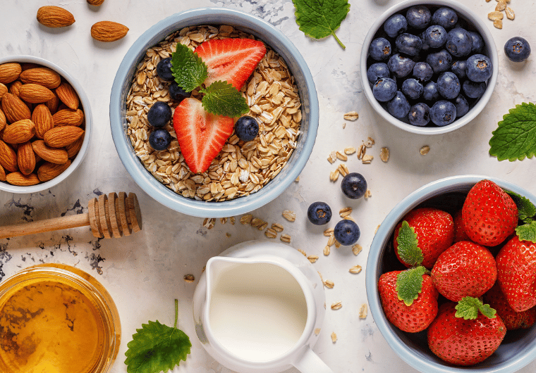Flat lay of healthy ingredients including strawberries, blueberries, almonds, oats, honey, and milk—perfect for easy snacks to make on busy weekdays