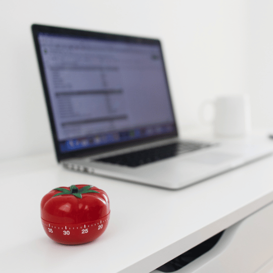 The Pomodoro Technique: How To Make it Work For You | Kitchen timer next to a computer