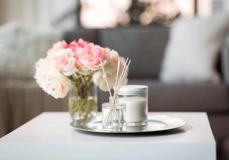 Elegant table setting with soft pink peonies, candle, and diffuser on a silver tray in a cozy living room. | Angelia Mendoza